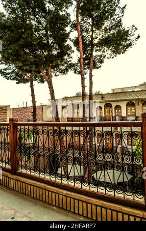 View from the last floor of the hotel  in Nor Julfa to the courtyard and tall pines, from a suspended long balcony with a fence made of patterned forg Stock Photo
