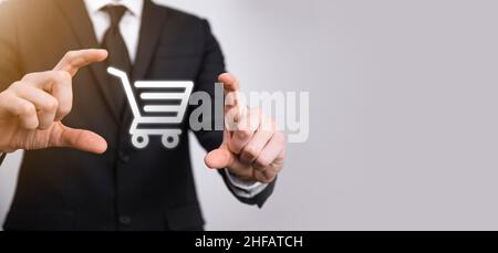 Business man hold in hand shopping cart icon.Shopping online concept.basket hologram. Online shopping, online store application in a smartphone. Digit Stock Photo