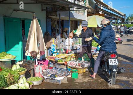 DALAT, VIETNAM - DECEMBER 28, 2015 : Woman on scooter buys fish on the street market Stock Photo