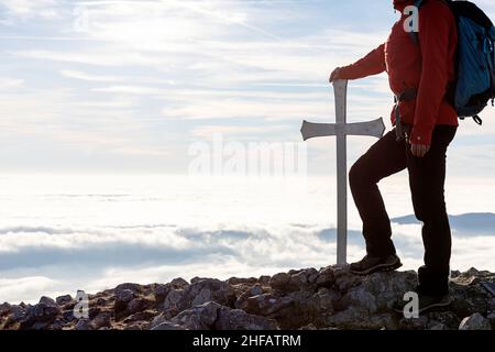 Woman standing by cross on the top of Kucelj mountain, Slovenia Stock Photo