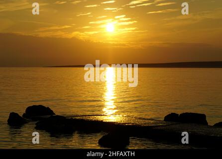 Stone pier wet of seawater during the golden hour at beautiful warm sunset Stock Photo