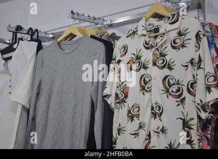 Casual t-shirts and shirts hanging on hangers in shop for sale - Stock Photo Stock Photo