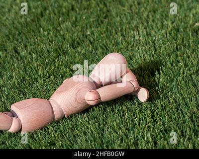 Human wooden doll lying on the grass relaxed sunbathing Stock Photo