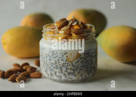 Overnight oats with mango and almonds. Made by soaking rolled oats and chia seeds in milk served with chopped mangoes, almonds and honey for a chilled Stock Photo
