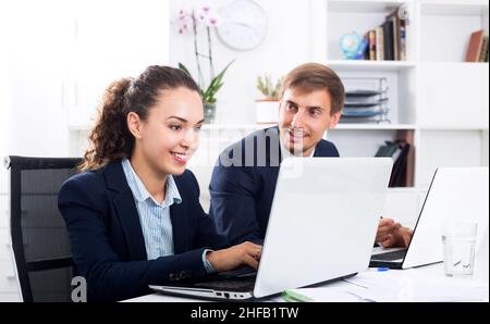 Two office workers work using laptops Stock Photo