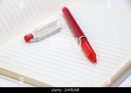 Red Pen and Pen Lid on a Blank Page of a Notebook Stock Photo