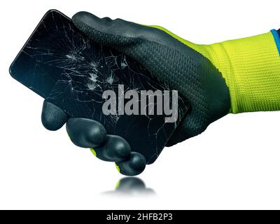 Hand with green and black protective work glove holding a modern smartphone with the broken touch screen, isolated on white background with reflection Stock Photo