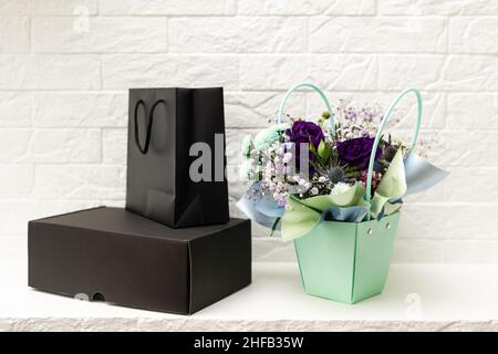 black empty paper bags and bouquets. Blank wall Stock Photo