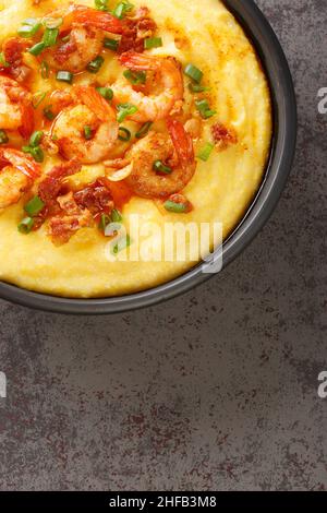 Homemade Shrimp and Grits with bacon and Cheddar closeup in the plate on the concrete table. Vertical top view from above Stock Photo