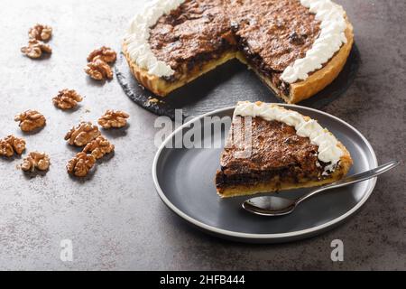 Sliced american chocolate walnuts pie with whipped cream closeup in a plate on the table. horizontal Stock Photo
