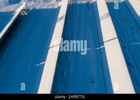 Aerial of solar panels covered with snow. Low efficiency during winter time in northern hemisphere. Stock Photo