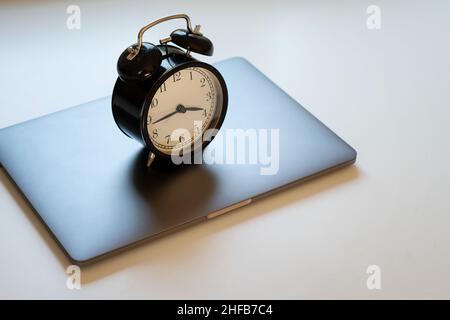 Alarm clock standing on laptop. Concept of work hours, deadline and limit screen time. Stock Photo