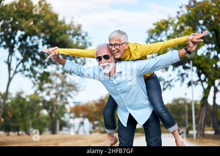 senior couple love together happy hug home family elderly man woman retirement smiling piggyback Stock Photo