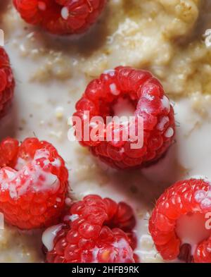 Close up of raspberries with milk on porridge. Healthy breakfast idea with berry fruits. Top view. Stock Photo
