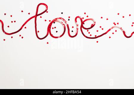Word Love made of red ribbon and confetti on white background. Happy Valentines Day concept Stock Photo