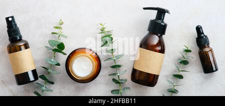 Natural organic cosmetics in amber glass bottles in row on stone table with eucalyptus. Beauty blog banner design. Skin care concept. Stock Photo