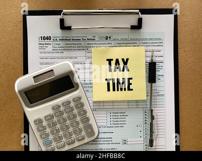 1040 US individual tax form, calculator, pen and tax time text on yellow sticker. Tax concept. Stock Photo