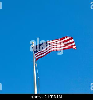 American flag waving against a brilliant blue sky Stock Photo