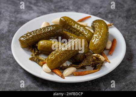 Pickled cucumbers on dark background. Close-up of pickled cucumbers in a ceramic plate. close up. Stock Photo