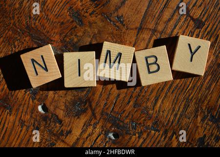 NIMBY, acronym for Not in My Back Yard, in wooden alphabet letters isolated on background Stock Photo
