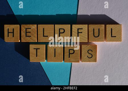 Helpful Tips, phrase in wooden alphabet letters isolated on blue and purple background Stock Photo