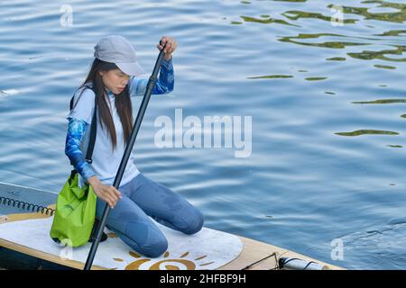 A young Thai woman, participant in a canoeing tour, canoeing on Klong (canal) Bangkok Yai in the Thonburi area of Bangkok, Thailand Stock Photo