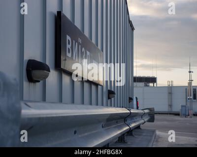 Directional exit right arrow sign in black and white on the metal wall at the rooftop parking of a shopping mall in the evening dusk. Stock Photo