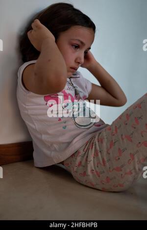 Bored little girl in isolation at home during quarantine COVID 19 Outbreak. Mental health Impact of coronavirus lockdown and social distancing. Stock Photo