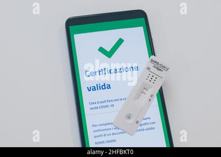 Closeup view of gloved hand with SARS-CoV-2 rapid antigen test nasal and phone with green digital certificate on display. Health, healthcare, corona v Stock Photo