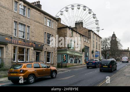 Lancaster, UK - 4th January 2020: A typical English street and road in city centre. Lancaster on Ice Big Wheel in the background with traffic and shop Stock Photo