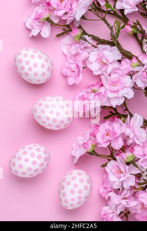 Easter background with polka dot paschal eggs, flat lay with cherry blossom tree branches. Spring season. Minimal design, festive floral greeting card Stock Photo