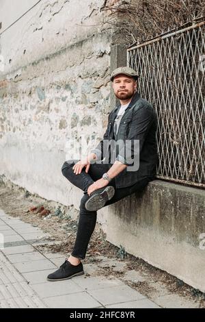 Portrait of a handsome guy with ivy hat leaning on the wall Stock Photo