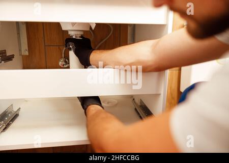 Closeup of hands of professional plumber fixing sink, changing water pipe in apartment Stock Photo