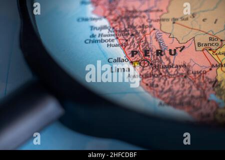 Peru on a world map through magnifying glass. Peru travel destination planning pinned Stock Photo