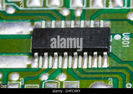 Electronic microchip soldered on a green printed circuit board (PCB). Stock Photo