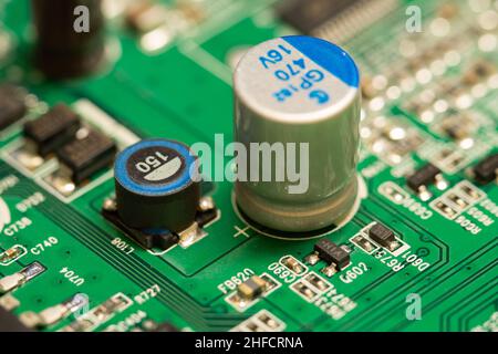 Electrolytic capacitor soldered on a green printed circuit board (PCB). Stock Photo