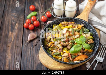 Seafood ragout, healthy mediterranean dinner. Seafood shrimps, calamari, cuttlefish stewed with vegetables and garlic sauce in a frying pan, on an woo Stock Photo