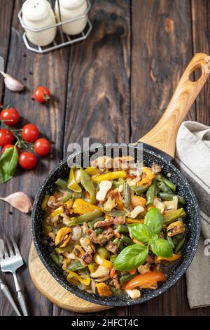 Seafood ragout, healthy mediterranean dinner. Seafood shrimps, calamari, cuttlefish stewed with vegetables and garlic sauce in a frying pan, on an woo Stock Photo