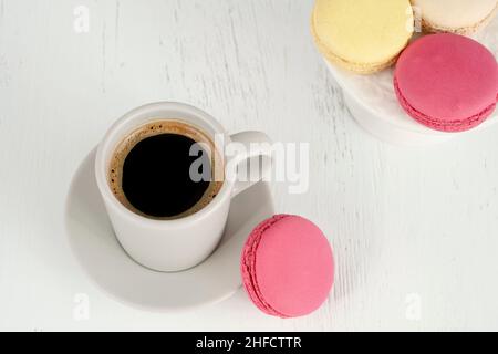 macaroons and coffee, colorful macaroons and cup of coffee on wooden table. delicious french cookies on wood background Stock Photo