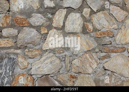 Stone wall made by hand using concrete. Yellow tones dominate.Background and closeup. Stock Photo