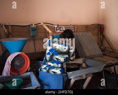 Woman tends a corn mill grinding masa in Jinotega, Nicaragua Stock Photo