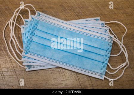 The several blue medical mask on a wooden plank surface, top view. Polypropylene masks for respiratory protection. COVID-19 concept. Stock Photo