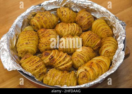 Accordion baked potatoes in the pot. Home cooking concept.