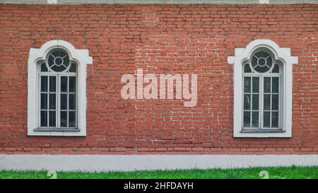Two windows in a row on brick wall of old house. Facade of old building. Stock Photo