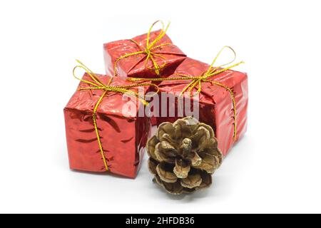 Three similar red gift boxes with with golden bow and fir cone isolated on white background. Christmas and holidays presents concept. Stock Photo