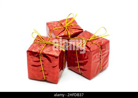 Three similar red gift boxes with with golden bow isolated on white background. Christmas and holidays present concept. Stock Photo