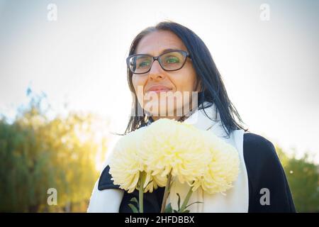 Profile side view portrait of attractive cheerful dreamy grey-haired middle-aged woman relaxing outdoors during sunny day Stock Photo