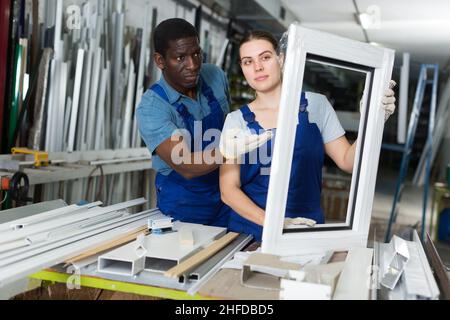 Portrait of man and woman worker who are standing with window frames Stock Photo