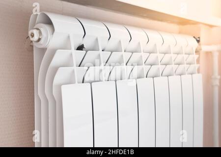 Close-up of modern home heating radiator under the window. Bimetal, aluminium radiator. Heating system. Morning light. Stock Photo