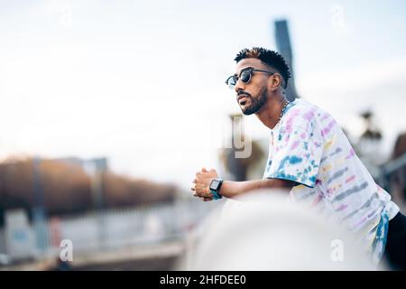 Black man with sunglasses leaning on the railing of a bridge pensive and relaxed Stock Photo